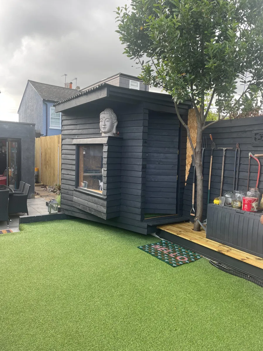 Black timber garden building beside decking